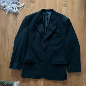 Grön kavaj från Carlo Romi - Elegant grön kavaj från Carlo Romi i en lyxig blandning av ull och kashmir. Kavajen har klassisk design med två knappar och fickor fram. Perfekt för en stilren look.