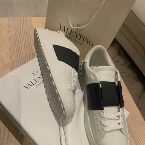 Valentino Garavani sneakers i vitt och svart - Säljer ett par riktigt Snygga Valentino Garavani sneakers i str 43 men passar 44 helt nya och helt o använda köpte för stor storlek riktigt feta o riktigt snygga! Allting kommer med priset ligger på 3000 men inte helt spikat vid mer frågor o funderingar så är det bara att skriva!