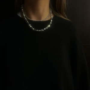 001 - Elegant silverfärgat halsband med glittrande pärlor. Perfekt för att ge en touch av glamour till din outfit. Halsbandet har en klassisk design som passar till många tillfällen.