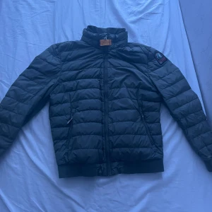 Parajumpers Jacka - Säljer en svart jacka från Pjs med broderad logga på ärmen. Jackan har dragkedja och är quiltad för extra värme. Perfekt för kyligare dagar. Den är i bra skick och är i storlek Y-M som passar mig som bär xs-s. 
