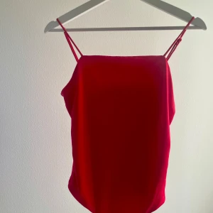 Röd body från Bik Bok - Snygg röd linnetopp/body från Bik Bok med tunna axelband. Perfekt för varma dagar eller som ett lager under en kavaj. Enkel och stilren design som passar till många olika outfits. Mjuk och smickrande passform med justerbara axelband. Två tryckknappar nertill. Använd fåtal gånger!