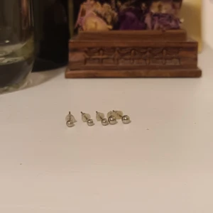 Set med små silverfärgade örhängen - Säljer ett set med sex små silverfärgade örhängen. Perfekta för en minimalistisk stil eller för att kombinera med andra smycken. De har en enkel och elegant design som passar till alla tillfällen.