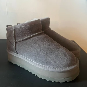 Grå boots från UGG - Säljer ett par grå boots från UGG med mjukt foder inuti. De har en klassisk design med rund tå och en robust sula. Perfekta för kyliga dagar.