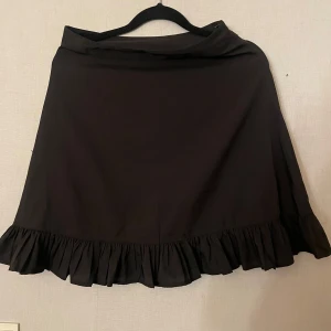 Svart kjol med volang från NA-KD - Snygg svart kjol från NA-KD med volangdetaljer längst ner. Använd 2 gånger 