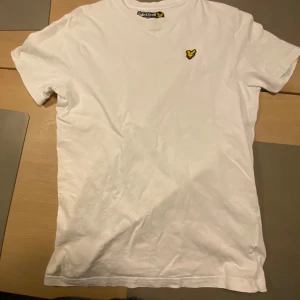 Vit t-shirt från Lyle & Scott - Säljer en klassisk vit t-shirt från Lyle & Scott med deras ikoniska gula logga broderad på bröstet. Storlek 12/13 år. Kan fraktas eller hämtas i Skövde.