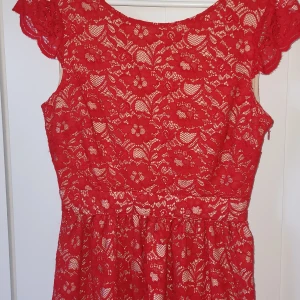 Röd spets klänning  - Kort röd spets klänning med öppen rygg  Kedja vid sidan  I mycket bra skick  Kan skicka fler bilder vid begäran  Kan ha smink fläckar på insidan som tvättas bort
