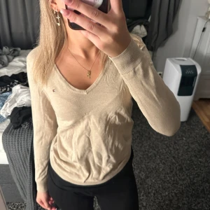 Tommy hilfiger tröja - Beige tröja med v-ringning ifrån Tommy hilfiger i strl M🩷