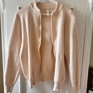 Beige stickad kofta från Fashion - Säljer en superfin beige stickad kofta från Fashion. Den har en dragkedja framtill och långa ärmar. Perfekt för höst och vår när det är lite kyligt ute. Koftan är i nyskick och väldigt mysig att ha på sig. 