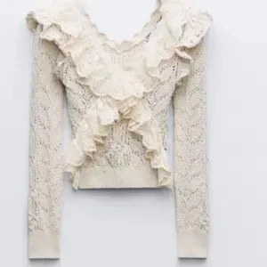 Beige spetsblus med volanger - Säljer en superfin beige spetsblus med volanger. Den har en v-ringad design och är croppad, vilket gör den perfekt för både vardag och fest. Blusen är långärmad och har en romantisk stil som passar perfekt till höst och vår. Den är i bra skick och redo för en ny ägare!