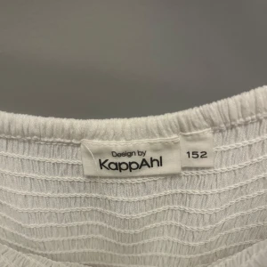 Vit klänning från KappAhl - Säljer en superfin vit klänning från KappAhl i storlek 152. Klänningen har en offshoulder-design med korta ärmar och en smockad överdel som ger en bekväm passform. Kjoldelen är luftig och perfekt för varma sommardagar.  Aldrig använd utan bara testad
