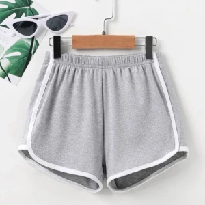 Grå shorts med vit kant - Säljer ett par grå shorts med vit kant. De är superbekväma och perfekta för en avslappnad dag. Shortsen har en elastisk midja och är gjorda i ett mjukt material. Perfekta för sommaren eller träning!