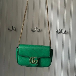 Gucciväska - GG marmont flap leather cross body bag. Superfin mindre väska! Grön med guldiga detaljer.  Sparsamt använd. Kan skickas mot frakt/hämtas upp i Lund.