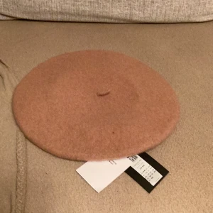 Beige ullbasker - Säljer en superfin beige basker i ull. Perfekt för höst och vinter, den är både stilren och varm. Baskern har en klassisk design och är i nyskick. Passar perfekt till en chic outfit!