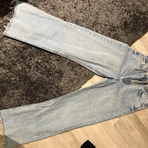 Ljusa jeans från Zara - Säljer ett par ljusa jeans från Zara med en avslappnad passform. De har en klassisk femficksdesign och råa kanter vid bensluten för en trendig look. De är raka i modellen och säljs för att de är stora !!