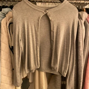 Kofta - Säljer en stilren grå kofta från 157 i storlek S. Koftan har långa ärmar och knappar framtill, perfekt för lager-på-lager-stil. Passar bra till både vardag och mer uppklädda tillfällen.