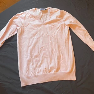 Ljusrosa tröja från Race Marine - Säljer en ljusrosa tröja från Race Marine med v-ringning. Tröjan har långa ärmar och ribbade kanter vid ärmslut och nederkant. Perfekt för en stilren look.