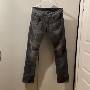 Grå jeansbyxor från Tommy Hilfiger - Snygga grå jeansbyxor från Tommy Hilfiger med en cool sliten look. Dom har en häftig liten silvrig logga på bakfickan. Dom har en loose passform och är perfekta för en avslappnad stil. Dom är väldigt mjuka och bekväma.