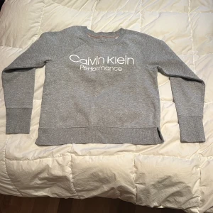 Grå sweatshirt från Calvin Klein Performance - Säljer en grå sweatshirt från Calvin Klein Performance. Tröjan har en rund halsringning och långa ärmar. Perfekt för en avslappnad stil med en snygg logga framtill. 👌🏼
