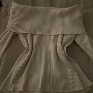 Vit ribbad offshoulder-tröja - Snygg vit offshoulder-tröja med ribbad design. Perfekt för en stilren look med långa ärmar och en bekväm/ tajt passform. Också aldrig använd.     Org pris: 279kr 
