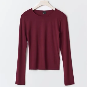 Vinröd långärmad topp - Snygg vinröd långärmad topp i mjukt material. Perfekt för en stilren look, med rund hals och figurnära passform. Passar utmärkt till både jeans och kjol.