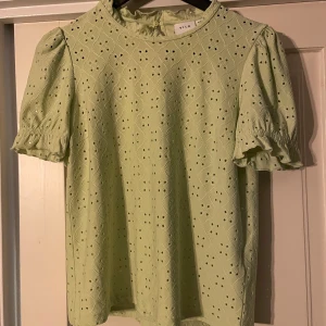 Ljusgrön blus från Vila - Säljer en söt ljusgrön blus från Vila med korta puffärmar och ett fint broderat mönster. Perfekt för vår och sommar!