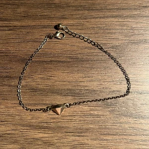 Guldarmband med pyramidberlock - Elegant guldarmband med en liten pyramidformad berlock. Kedjan är tunn och smidig med ett enkelt lås. Perfekt för att lägga till en subtil touch av stil till din look. Inte äkta guld