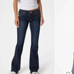 Mörkblå bootcut jeans - Snygga mörkblå bootcut jeans med låg midja och klassisk femficksdesign. Jeansen har dekorativa sömmar och knappar på bakfickorna. Perfekta för en avslappnad stil. Längden är 32