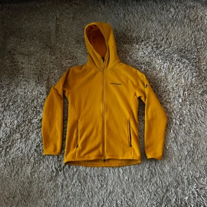 Fleecehoodie Peak Performance - Säljer en gul fleecehoodie från Peak Performance då den inte kommer till användning. Gul, storlek M och i mycket bra skick, knappast använd. Perfekt nu inför vintern och skidsäsongen! Skriv vid minsta lilla fundering! ⛷️🏂