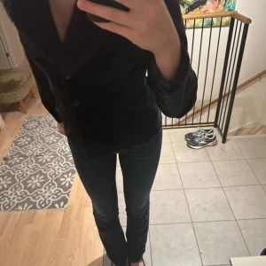 Svart kavaj från VILA - Snygg svart kavaj från VILA med klassisk design. Perfekt för en stilren look. Kavajen har långa ärmar och knappar framtill. Har fuskpälskrage. 