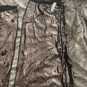 Glittrig kjol från Lindex - Snygg kjol från Lindex i silver med paljetter. Perfekt för att sticka ut på festen. Kjolen har en elastisk midja för bekväm passform. Nypris 499kr