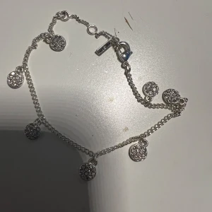 Pilgrim Silverarmband med glittriga berlocker - Elegant silverarmband med flera glittriga berlocker. Perfekt för att ge en gnistrande touch till din outfit. Armbandet har en fin kedja och är lätt att justera i storlek. Från pilgrim. Nypris 400kr