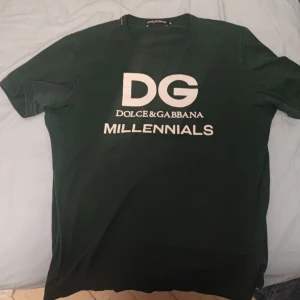 Grön t-shirt från Dolce & Gabbana - Snygg grön t-shirt från Dolce & Gabbana med texten 'DG Millennials' i vitt på framsidan. Perfekt för en stilren och modern look. Tillverkad i Italien.         Köptes för ca 4700 kri New York hos D&G. Säljs för endast 1250 kr