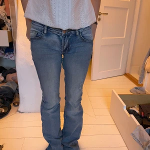 Blå jeans med bootcut - Säljer ett par blå jeans med bootcut-stil. De har en klassisk femficksdesign och en lågmidjad passform. Perfekta för en avslappnad look.