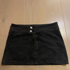 Svart jeanskjol - Snygg svart jeanskjol med två knappar framtill och en bakficka. Använd 1 gång