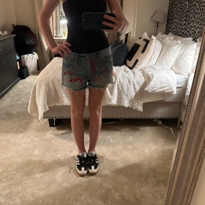 Levis shorts med röda detaljer - Snygga jeansshorts från Levi's med fransiga kanter och coola röda detaljer. Perfekta för en avslappnad stil med en twist. Klassisk femficksdesign och knappgylf.