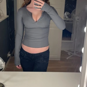 Grå långärmad topp med knappar - Snygg grå långärmad topp med knappar framtill. Perfekt för en stilren look. Passar bra till både jeans och kjol. Aldrig använd. Passar mig som använder S.🩵🤍