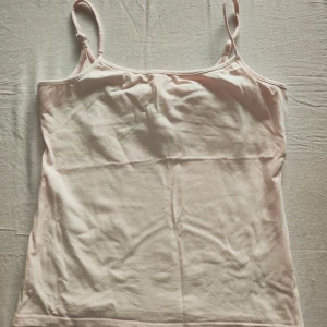 Ljusrosa linnetopp från b.young - Säljer en ljusrosa linne med inbyggd topp från b.young. Toppen har smala axelband och är tillverkad i ett mjukt bomullsmaterial. Perfekt för varma dagar eller som ett basplagg i garderoben.