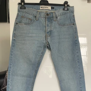 Ljusblå skinny jeans från Topman 28’ - Snygga ljusblå skinny jeans från Topman. De har en klassisk femficksdesign och knappar i gylfen. Perfekta för en stilren look. Midjemått 76 cm , Innerbenslängd 74 cm 