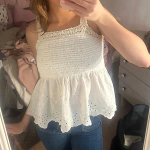 Vit ärmlös topp med spetsdetaljer - Söt vit ärmlös topp med spetsdetaljer och volang. 