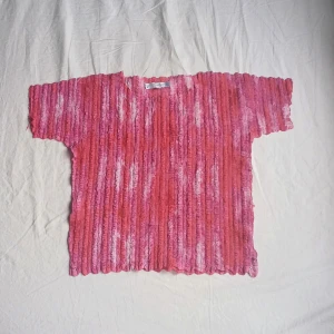 Rosa ribbad topp - Säljer en unik rosa ribbad topp med korta ärmar. Toppen har ett intressant mönster i olika nyanser av rosa och vitt. Perfekt för att ge din outfit en färgglad touch!