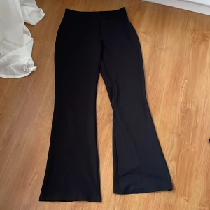 Svarta vida byxor boycott - Snygga svarta byxor med en elegant och vid passform. Perfekta för en stilren look. Byxorna har en hög midja och är tillverkade i ett mjukt material som ger en bekväm känsla.