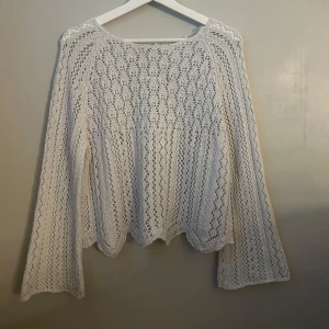 Vit stickad tröja - Säljer en vit stickad tröja med ett vackert spetsmönster. Tröjan har långa ärmar och en lös passform, perfekt för lager på lager-stil. Den är både stilren och bekväm. Har ett litet hål men inget som syns och är lätt att fixa🧞‍♀️🧚🏼‍♀️🦄