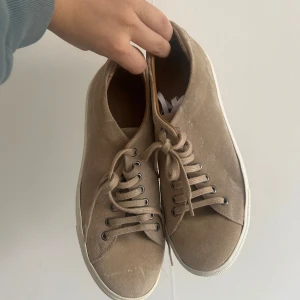 Herr Beige sneakers med snörning - Snygga beige sneakers med snörning och vit sula. Perfekta för en avslappnad stil. Skorna har en klassisk design med rund tå och är tillverkade i mocka.
