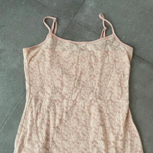Beige spetslinne - Säljer ett sött beige spetslinne med smala axelband. Perfekt för en somrig look eller som ett lager under en annan topp. Linnet är i ett mjukt och stretchigt material som ger en bekväm passform.