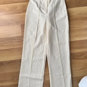 Beige kostymbyxor - Snygga beige kostymbyxor med hög midja och rak passform. Helt nya aldrig använda bara testade  Perfekta för en stilren look. Byxorna har en klassisk design med pressveck framtill.