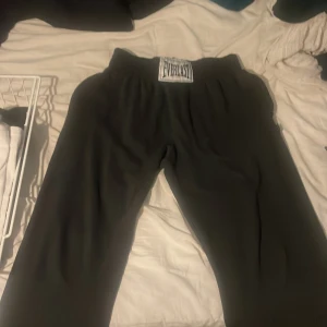 Svarta mjukisbyxor från Everlast - Säljer ett par svarta mjukisbyxor från Everlast. De har en elastisk midja och är perfekta för en avslappnad stil. Byxorna är bekväma och passar bra för träning eller hemmamys.