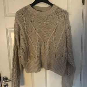 Beige stickad tröja - Säljer en mysig beige stickad tröja med ett snyggt mönster. Tröjan har långa ärmar och en rund halsringning. Passar bra till både jeans och mjukisbyxor.