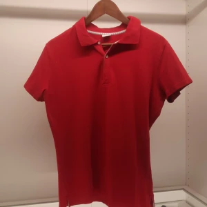 Röd pikétröja från Boomerang - Säljer en klassisk röd pikétröja från Boomerang i storlek XL. Tröjan har korta ärmar och en stilren krage med knappar framtill. Perfekt för en avslappnad och stilren look.