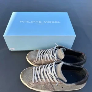Grå sneakers från Philippe Model - Snygga grå sneakers från Philippe Model med vit sula och klassisk snörning. Skorna har en stilren design med en diskret logga på sidan. Perfekta för en avslappnad och trendig look.
