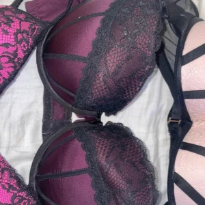 Lila och svart spets-bh - Elegant lila bh med svarta spetsdetaljer och blommigt mönster. Den har en vacker design med spets som ger en lyxig känsla. Perfekt för att känna sig extra fin.